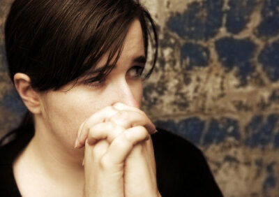 headshot of a fearful woman with hands folded in prayer
